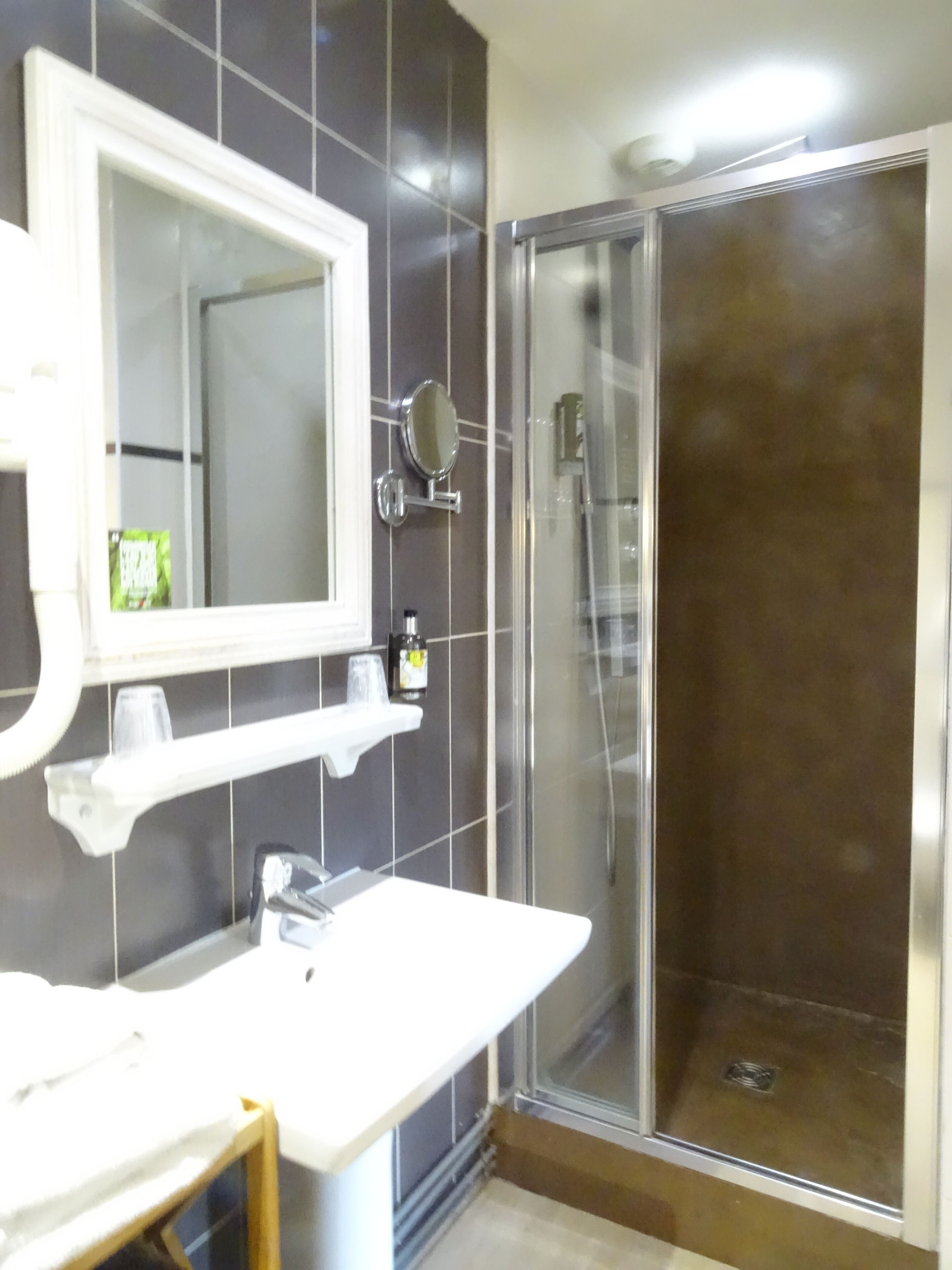 Un bagno con lavandino bianco, uno specchio e cabina doccia in vetro.