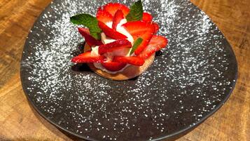 A dessert on a black plate with powdered sugar.