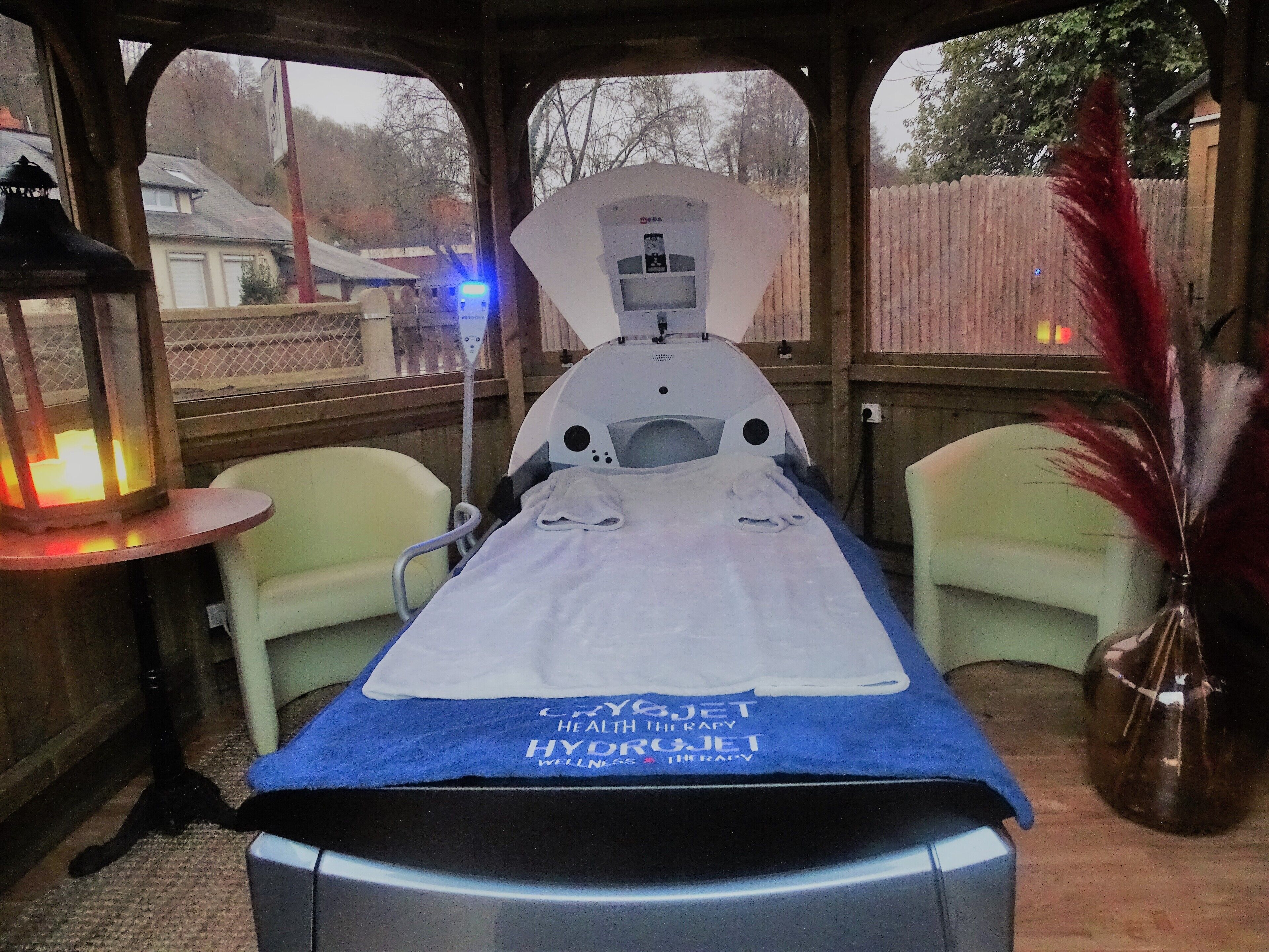 Een hydrotherapie tafel met een blauwe handdoek, een stoel en een lamp.