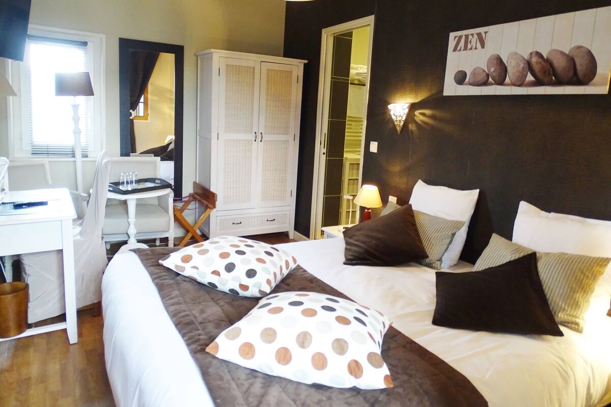 Una habitación de hotel con cama, escritorio, armario y espejo.