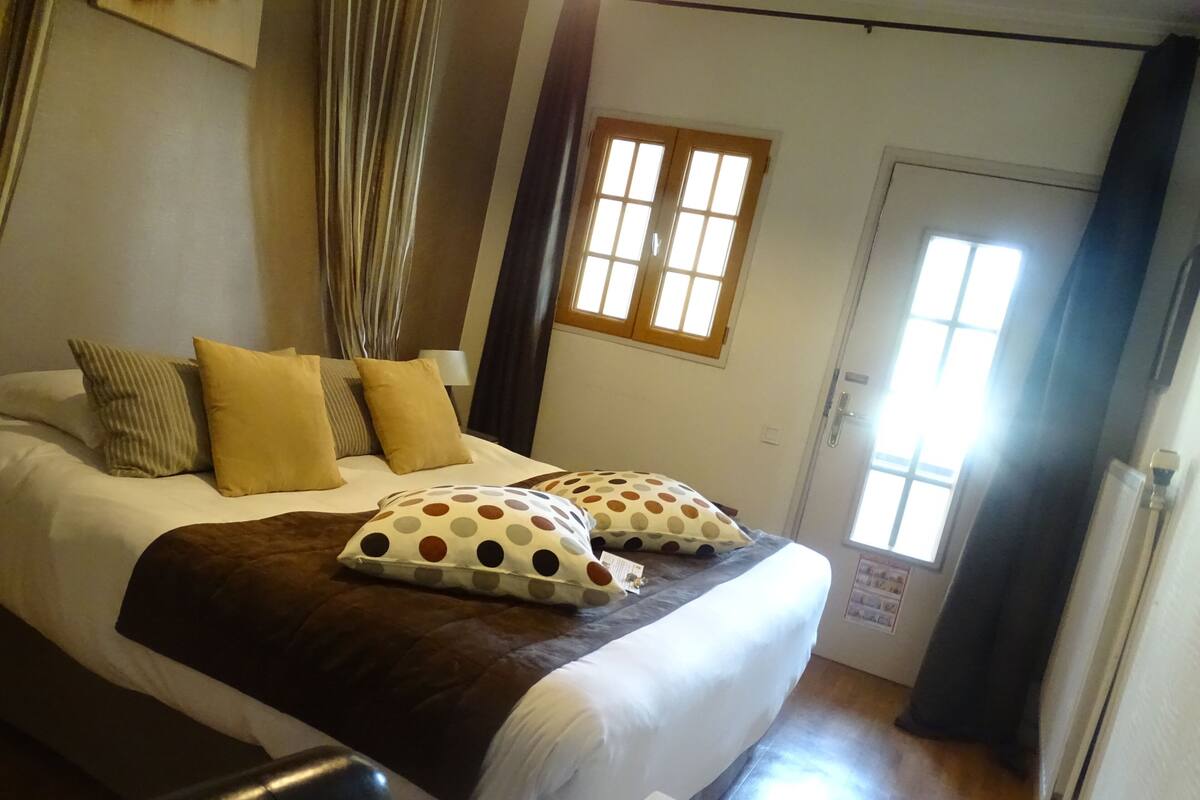 Una habitación de hotel con cama, almohadas, una ventana y cortinas.