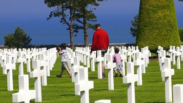 Ein Friedhof mit weißen Kreuzen und einem Gewässer im Hintergrund.