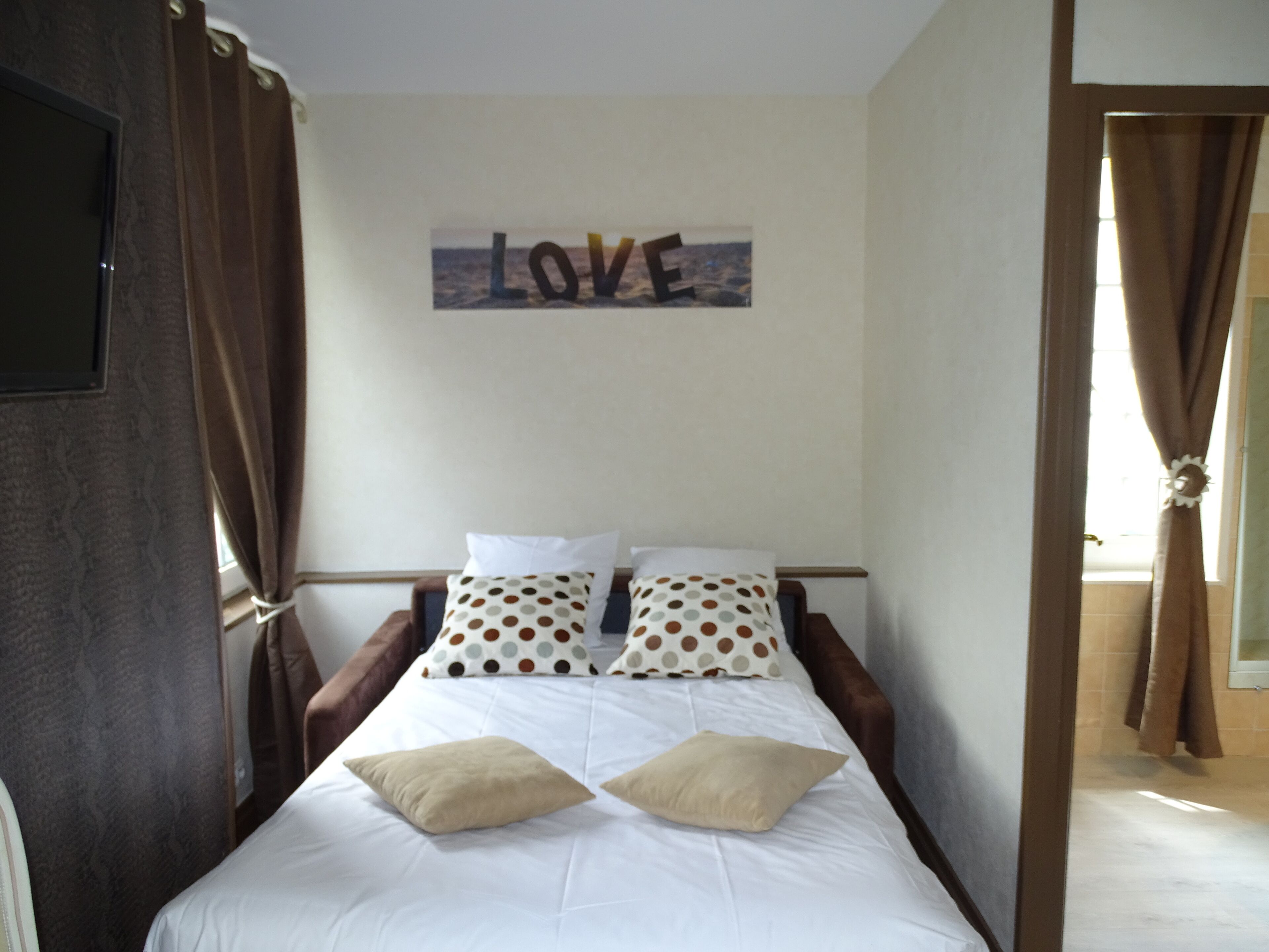 Ein Schlafzimmer mit einem Bett, zwei Kissen, einem Wandbild und Vorhängen.
