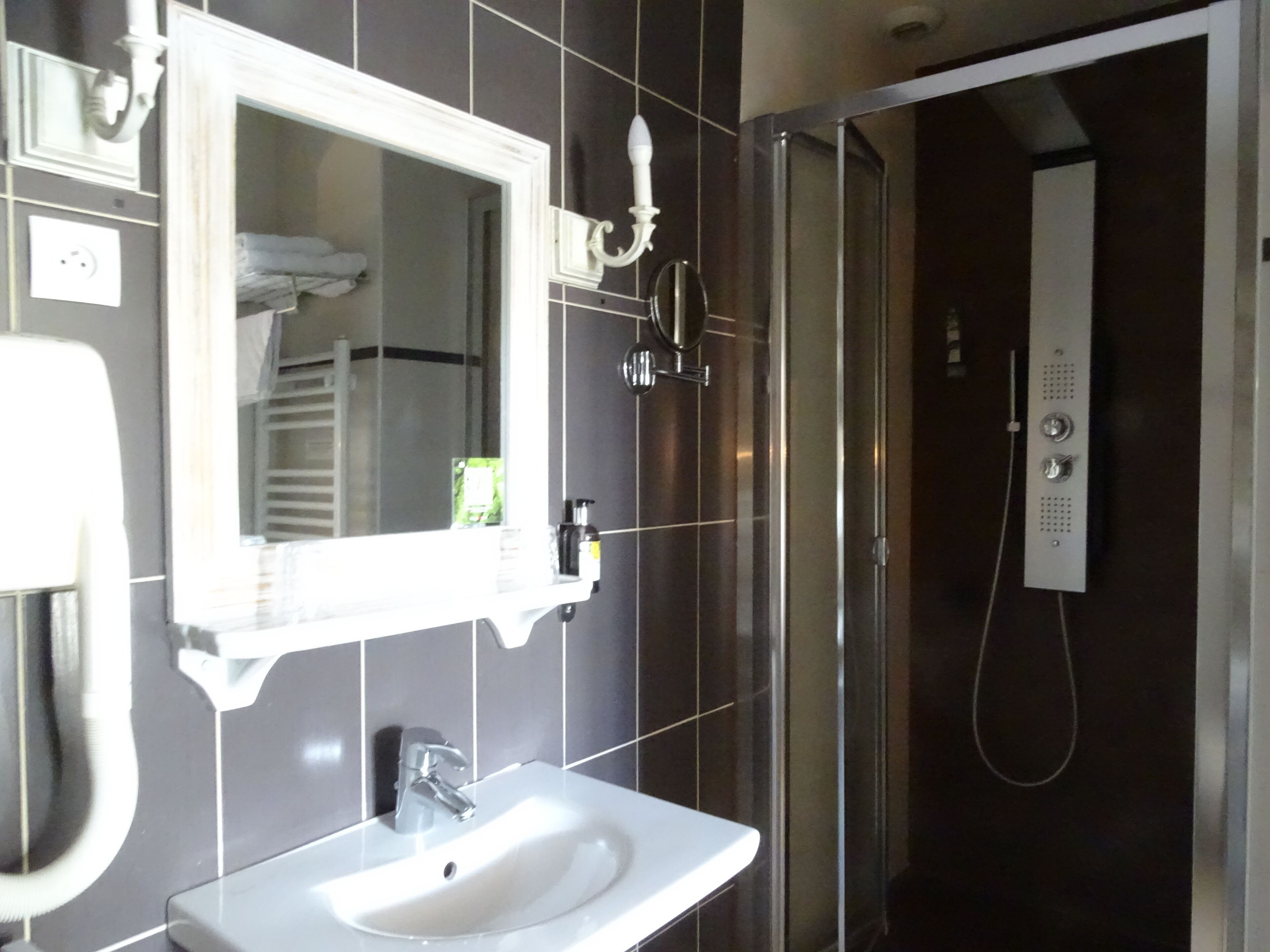 Un baño con lavamanos blanco, espejo y cabina de ducha.