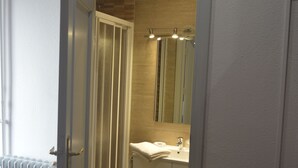 Un baño estrecho con tocador de madera, un espejo y un radiador.