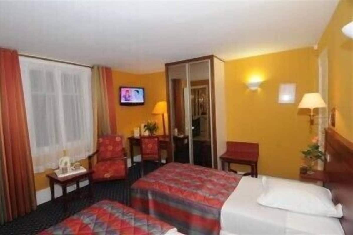 A hotel room with two beds, a television, a desk, a chair, and a window with curtains.