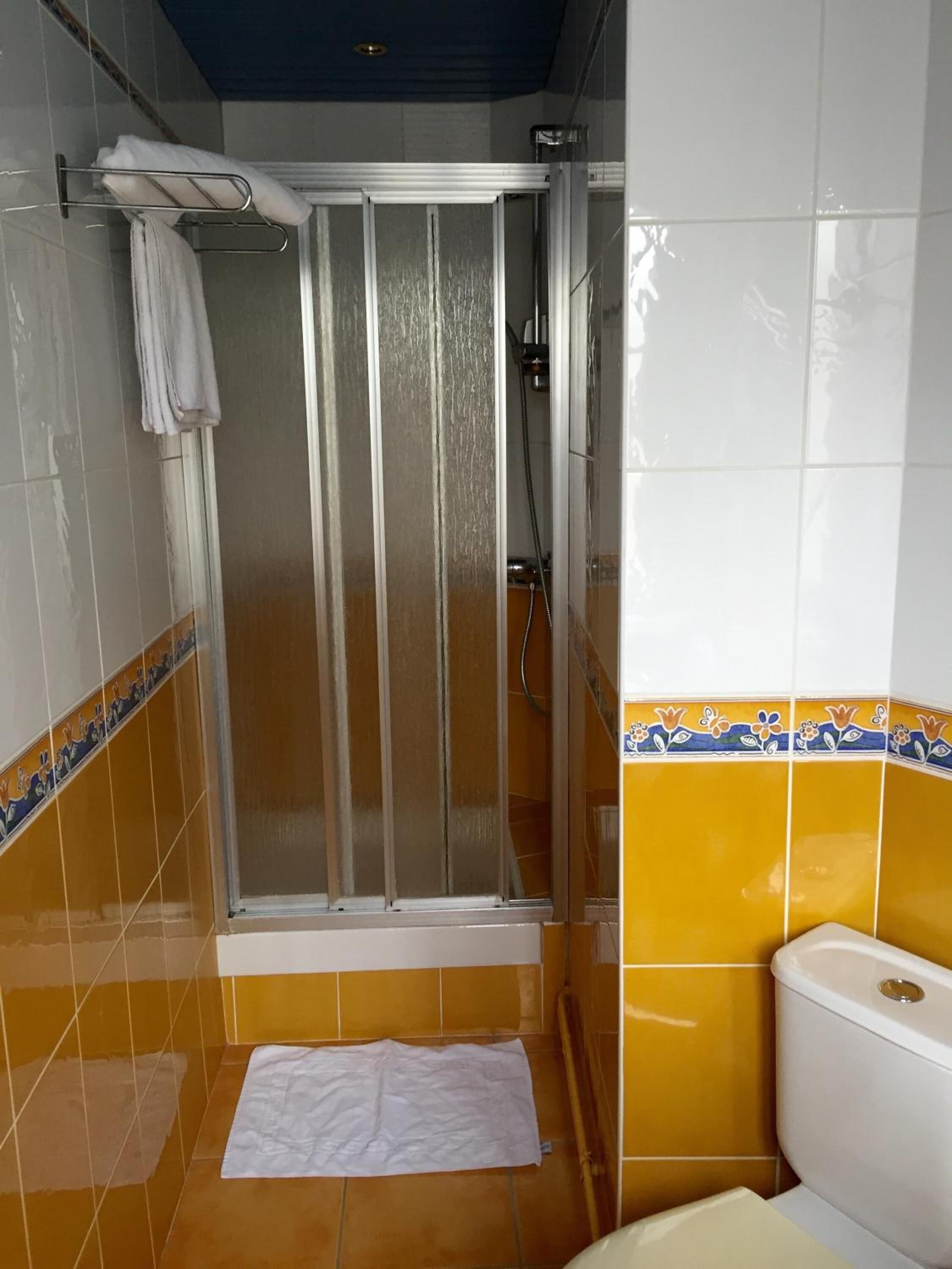 Un baño con cabina de ducha, inodoro y lavamanos.
