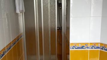 Un baño con cabina de ducha, inodoro y lavamanos.