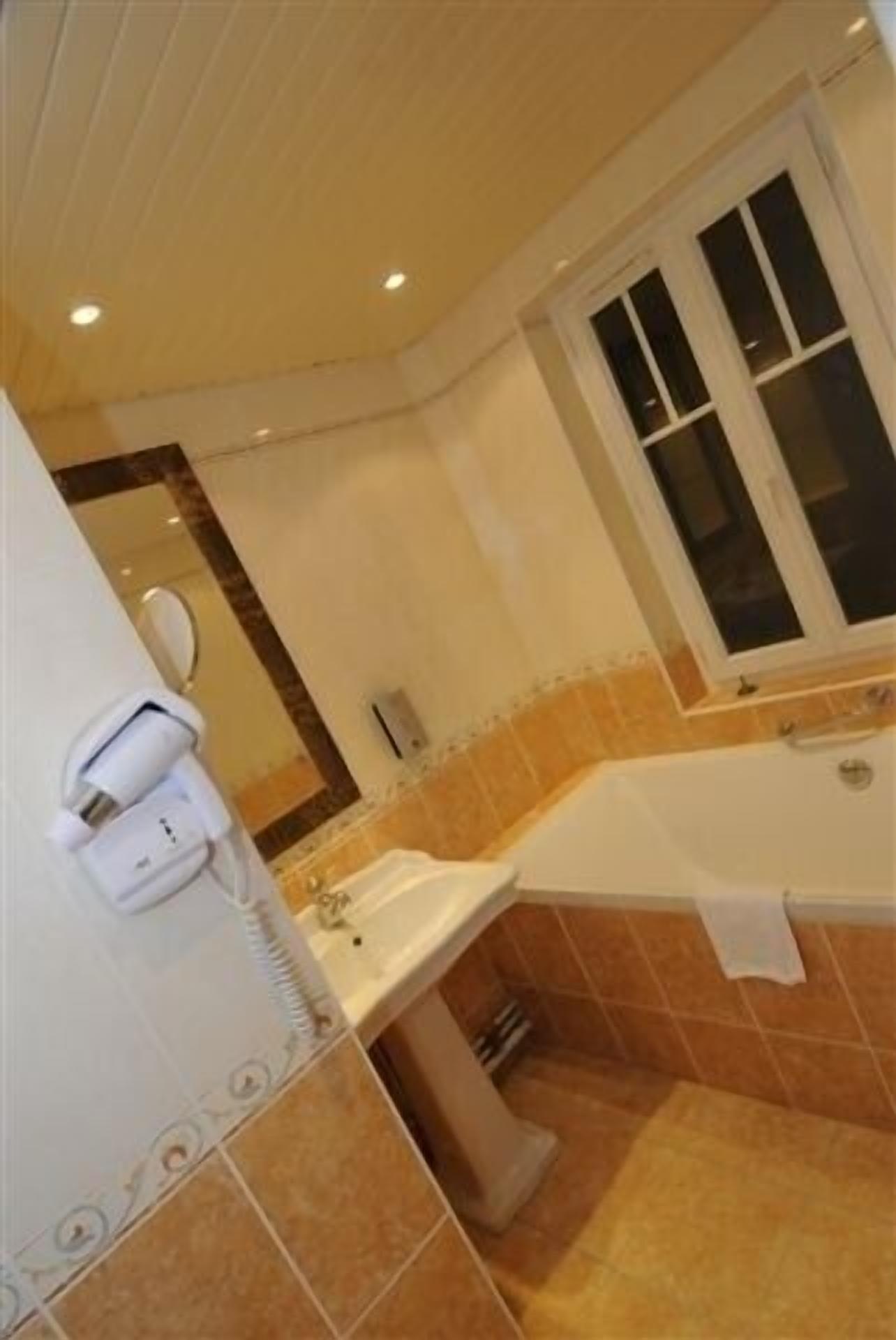 A bathroom with a sink, mirror, and window.