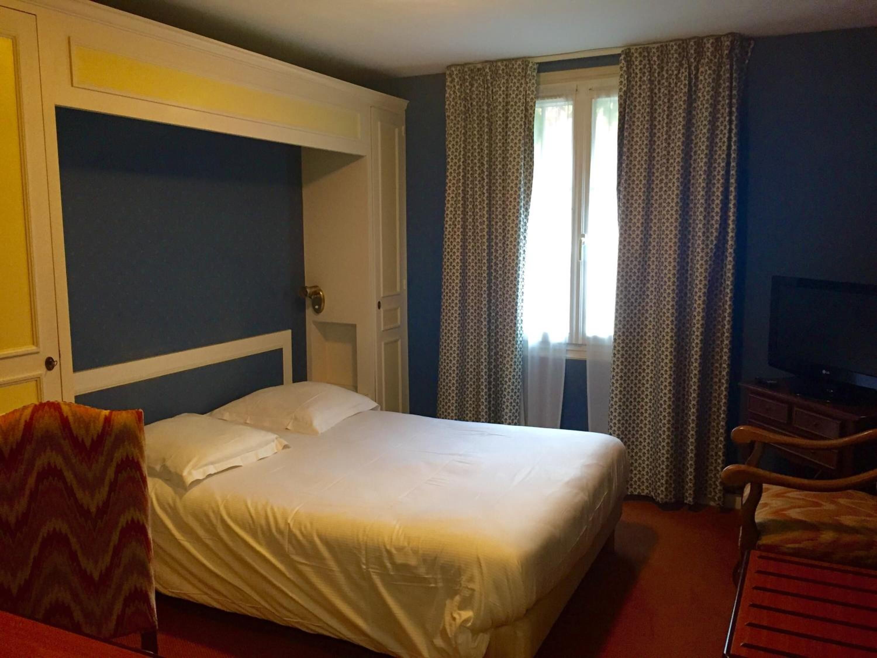 Ein Hotelzimmer mit einem Bett, einem Fernseher, einem Schreibtisch und einem Stuhl.