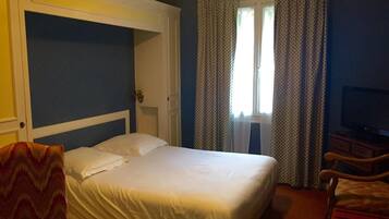 A hotel room with a bed, a television, a desk, and a chair.