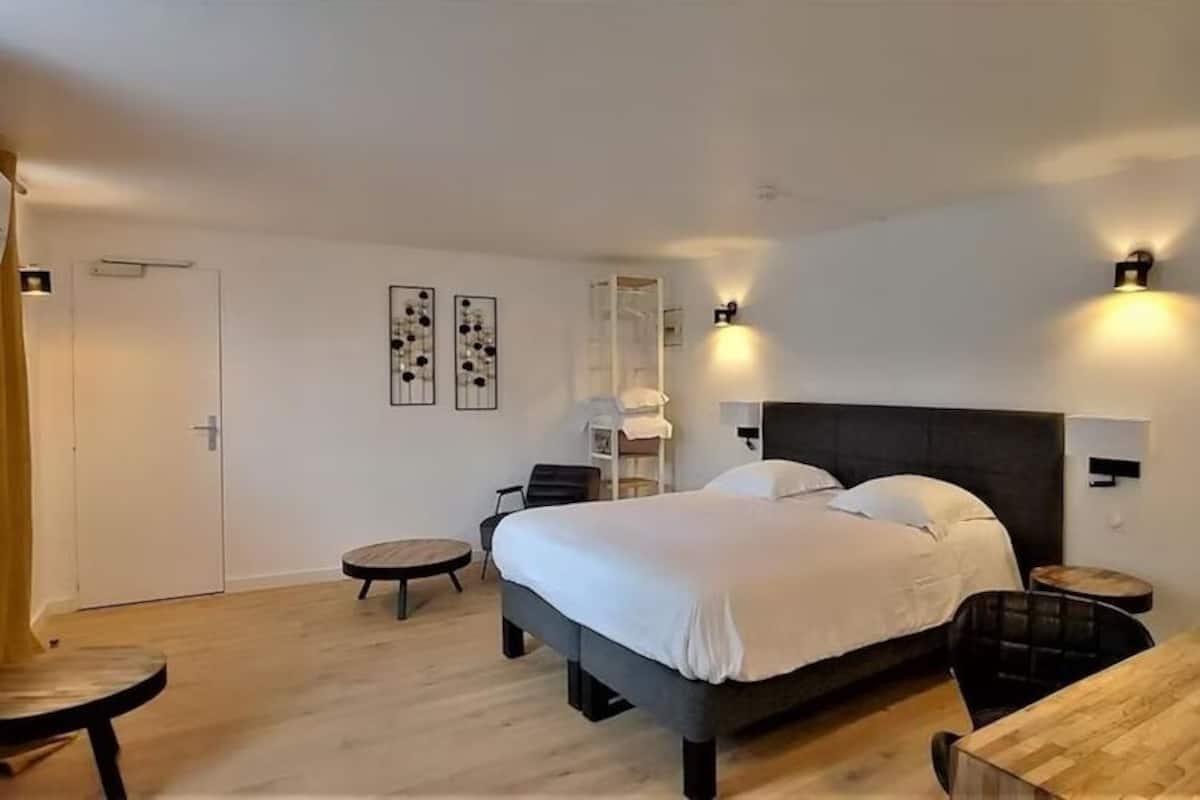 A modern hotel room with a large bed, bedside tables, a desk, and a chair.