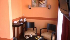 A small, cozy room with two chairs, a table, and a wall-mounted painting. - Hôtel d'Angleterre (Saint-Calais)