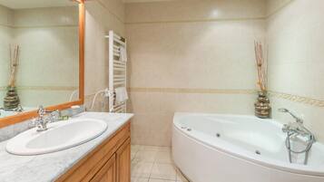 Un baño con dos lavamanos, una bañera y un espejo.