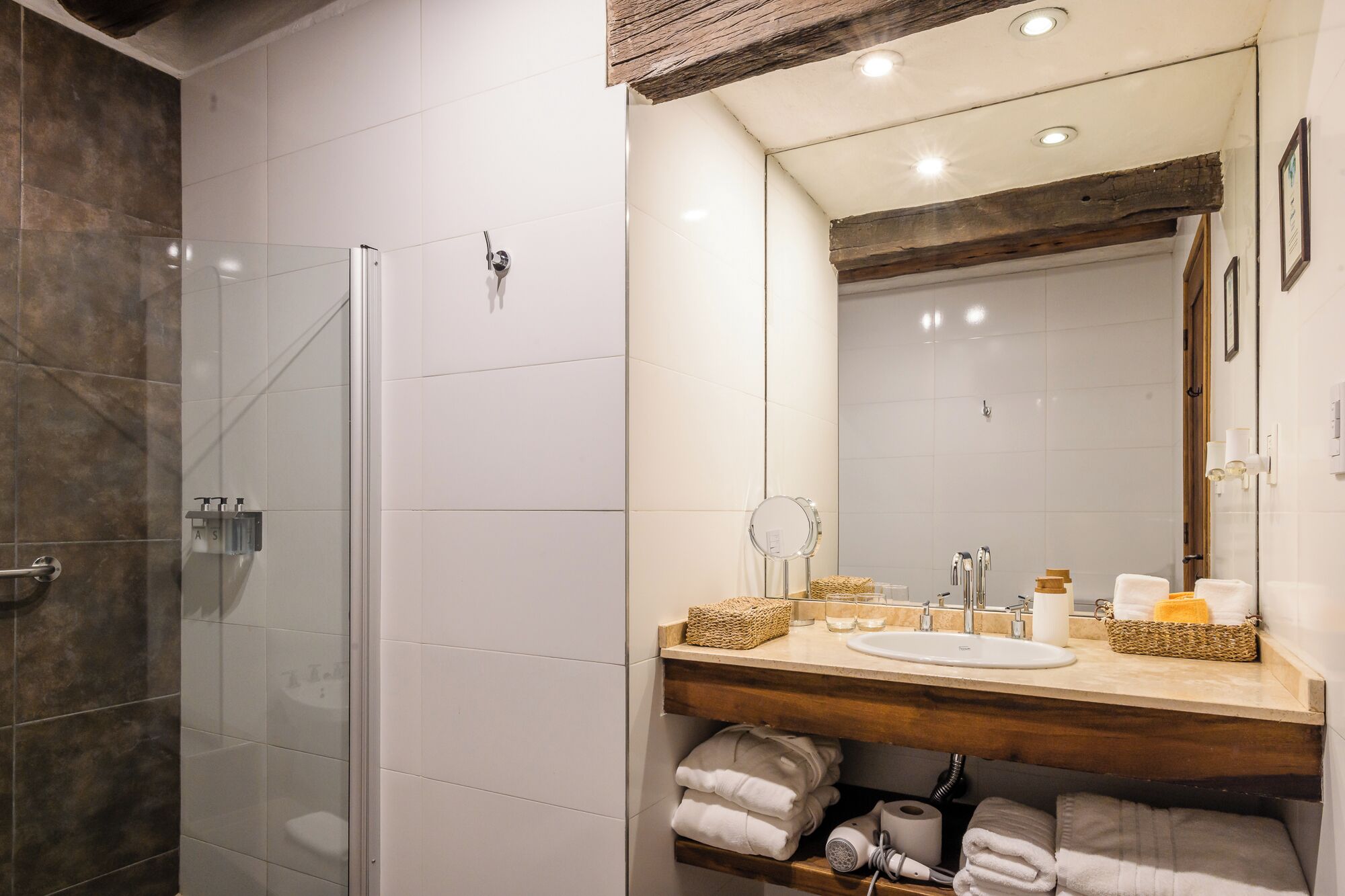 Een moderne badkamer met een douchecabine van glas, een houten wastafelmeubel en een grote spiegel.