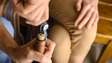 A person opening a wine bottle with a corkscrew.