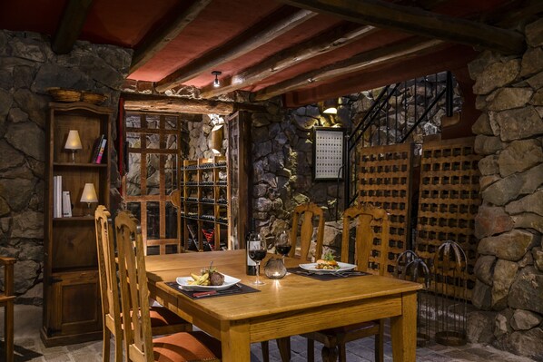 Un comedor rústico con paredes de piedra, muebles de madera y una alacena para vinos.