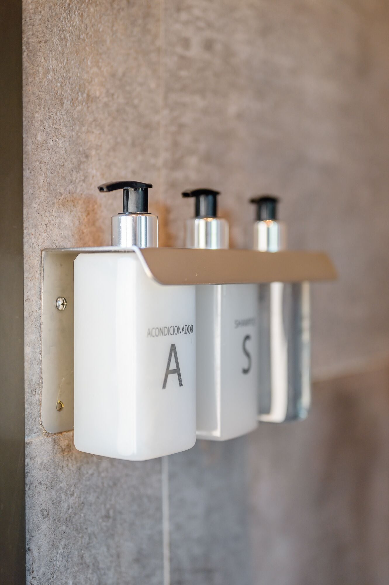 Un dispenser di sapone montato a parete con un erogatore, etichettato 'Acondicionador' e 'S'.