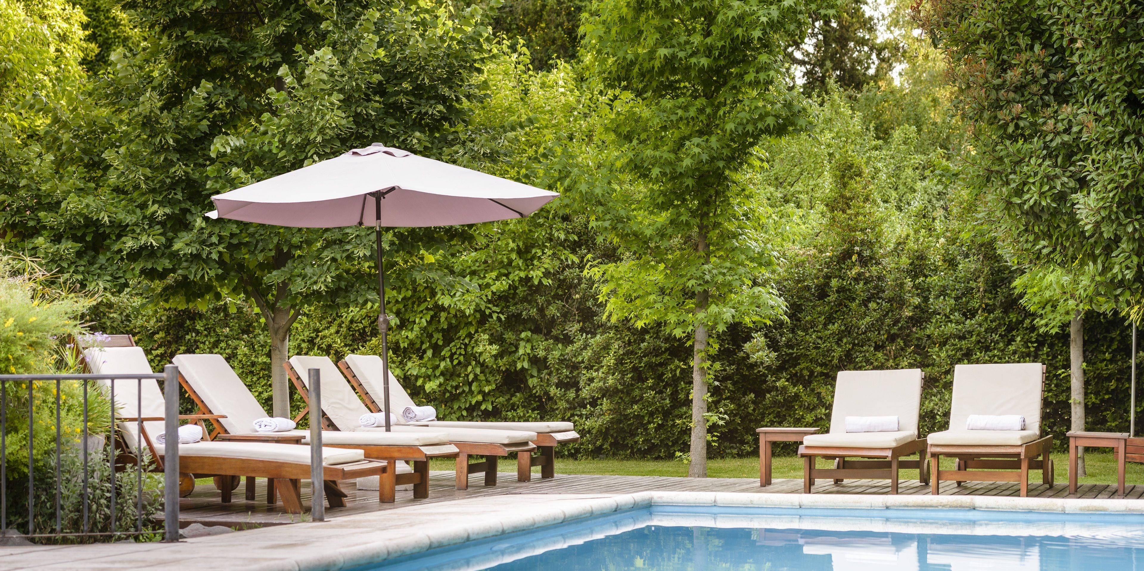 Un área junto a la piscina con sillones de descanso y una pérgola.