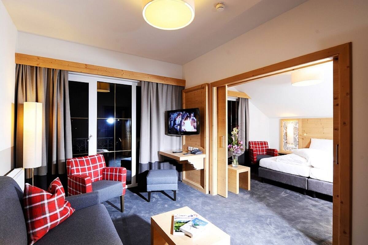 Habitación de hotel con sofá, escritorio, televisor, cama y vistas al exterior.