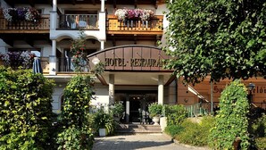 Entrada de un hotel con un cartel que dice "HOTEL RESTAURANT", rodeada de abundante vegetación y plantas en macetas.