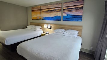 A hotel room with two beds, a nightstand, a phone, and a painting above the beds.