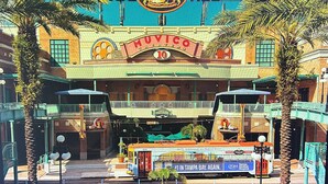 Un cinéma avec une enseigne lumineuse indiquant « Muvico 10 » et un panneau pour « TropiYBOP ».