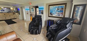 A massage therapy room with two massage chairs, a reception desk, and a painting on the wall. - Days Inn & Suites by Wyndham Tampa/Fairground/Casino Area (Tampa)