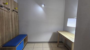 A small room with a wooden bench, a table, and a wall-mounted light fixture.