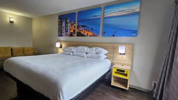 A hotel room with a bed, a sofa, a nightstand, and wall-mounted lights.