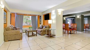 Une chambre d’hôtel comprenant deux canapés, une table basse, un téléviseur et un coin repas avec des chaises et une table.