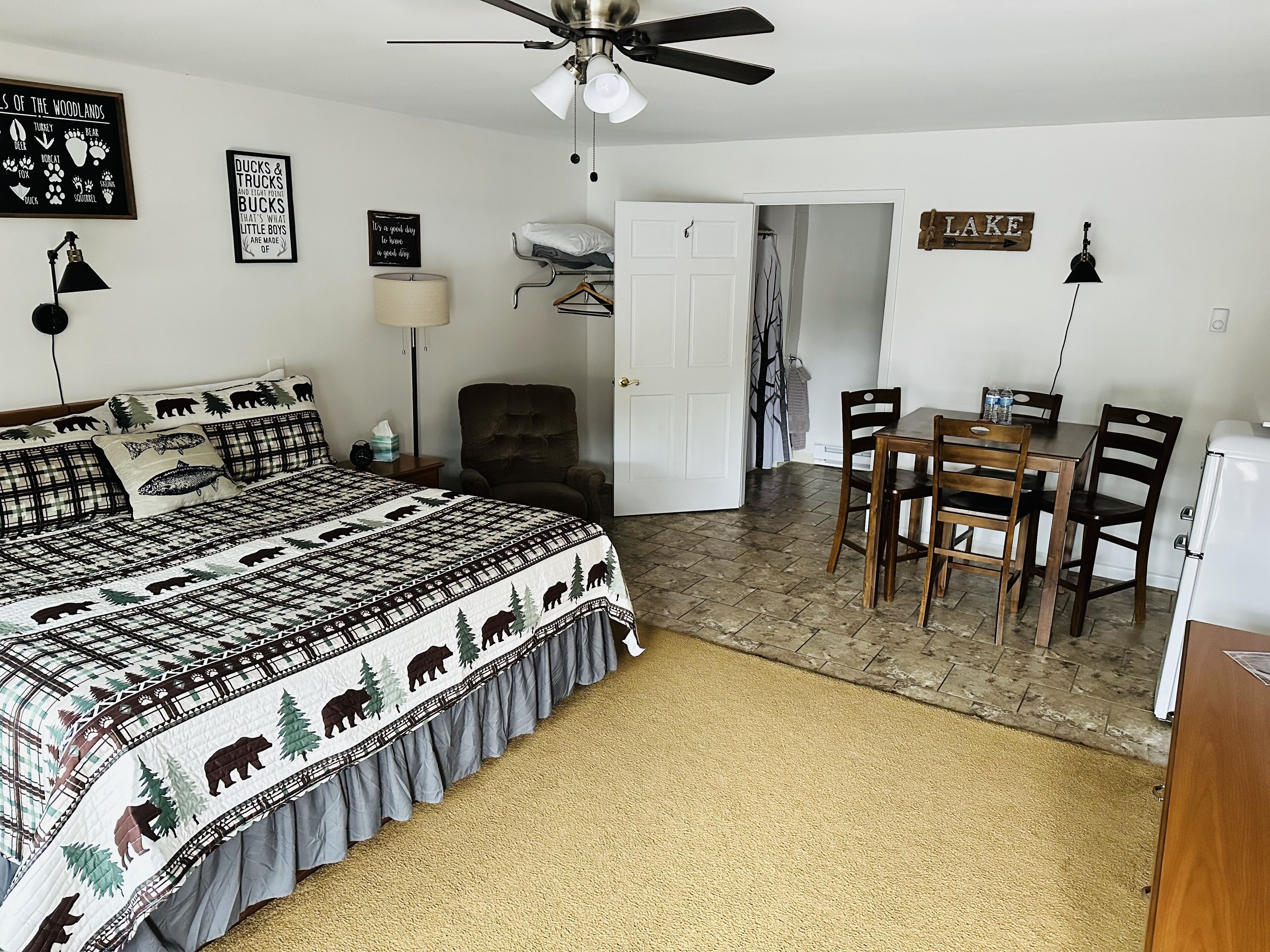 A bedroom with a bed, a chair, a table, and a ceiling fan.