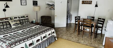 A bedroom with a bed, a chair, a table, and a ceiling fan.