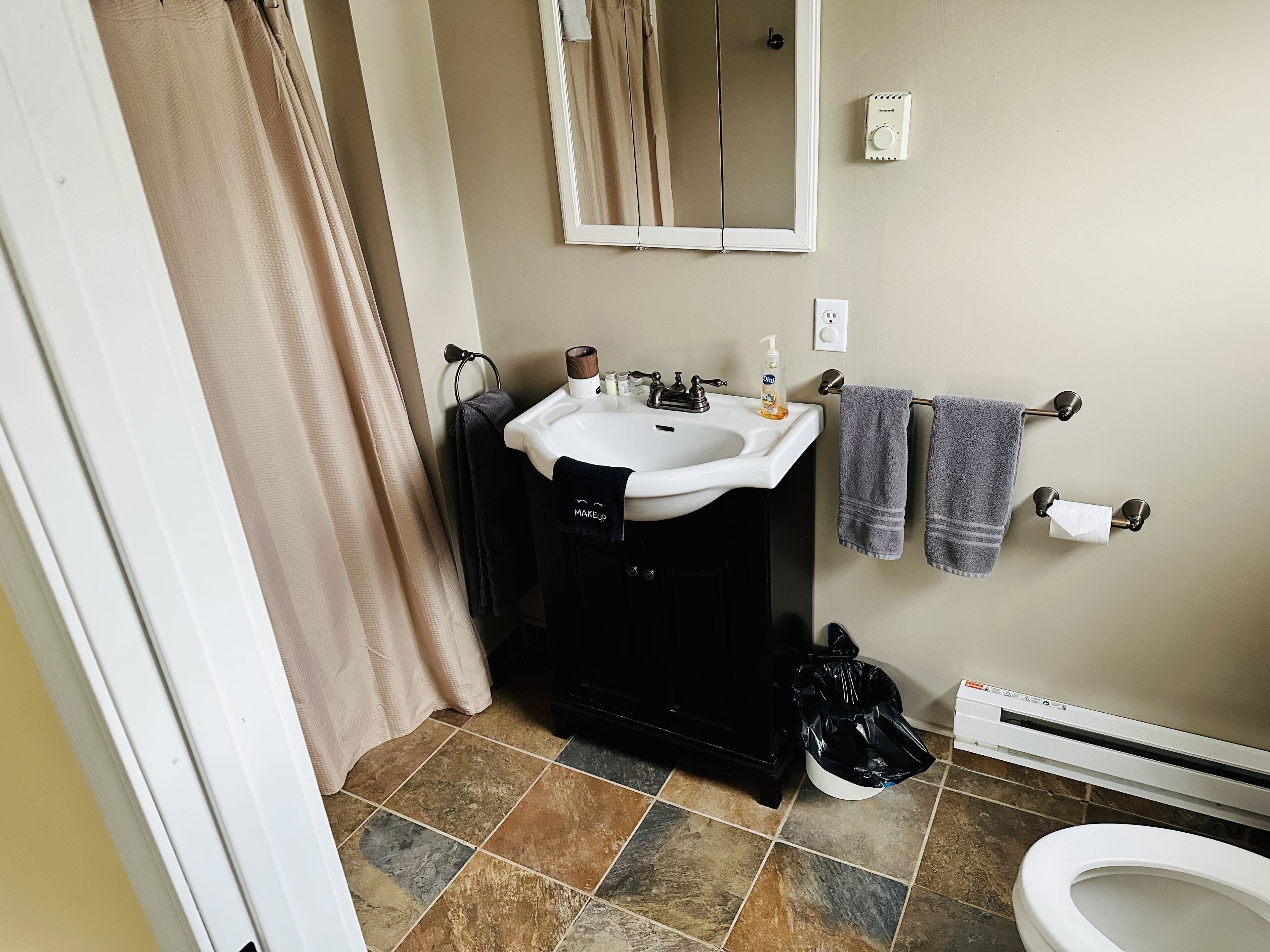 Une salle de bain équipée d’un lavabo, d’un miroir, d’un porte-serviettes, de toilettes et d’un appareil de chauffage.