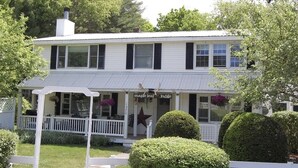 Un bâtiment blanc à deux étages, doté d’un porche, portant l’inscription « Maple Leaf Lodge ».