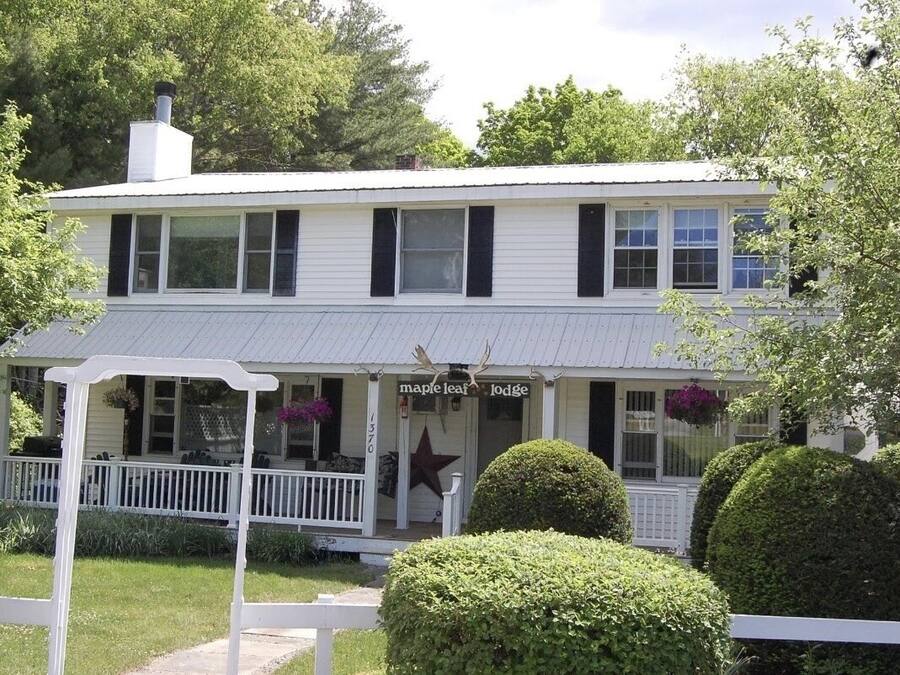 A two-story white building with a porch, labeled "Maple Leaf Lodge".