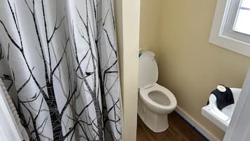 A bathroom with a toilet, a sink, and a shower curtain with a tree pattern.