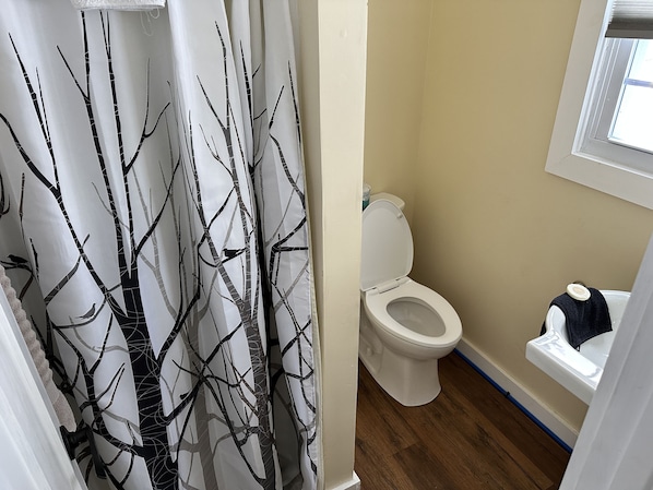 Un baño con inodoro, lavamanos y cortina de ducha con estampado de árboles.