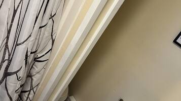 A bathroom with a white sink, a black towel, and a white shower curtain with a tree pattern.