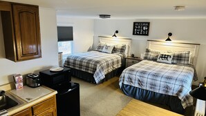 Une chambre avec deux lits, une armoire en bois, un four à micro-ondes, un grille-pain et une petite table.