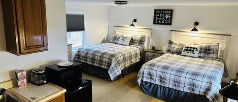 A bedroom with two beds, a wooden cabinet, a microwave, a toaster, and a small table.