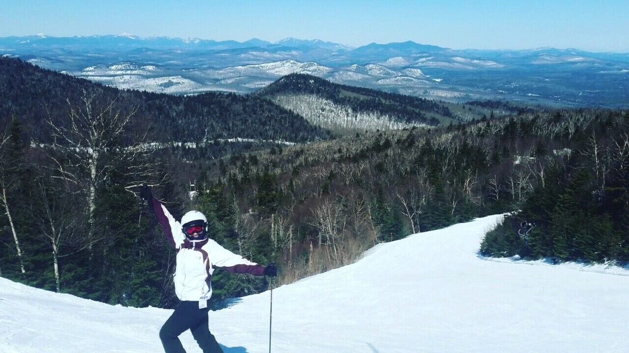 Una persona esquiando en una pendiente nevada con un paisaje montañoso al fondo.