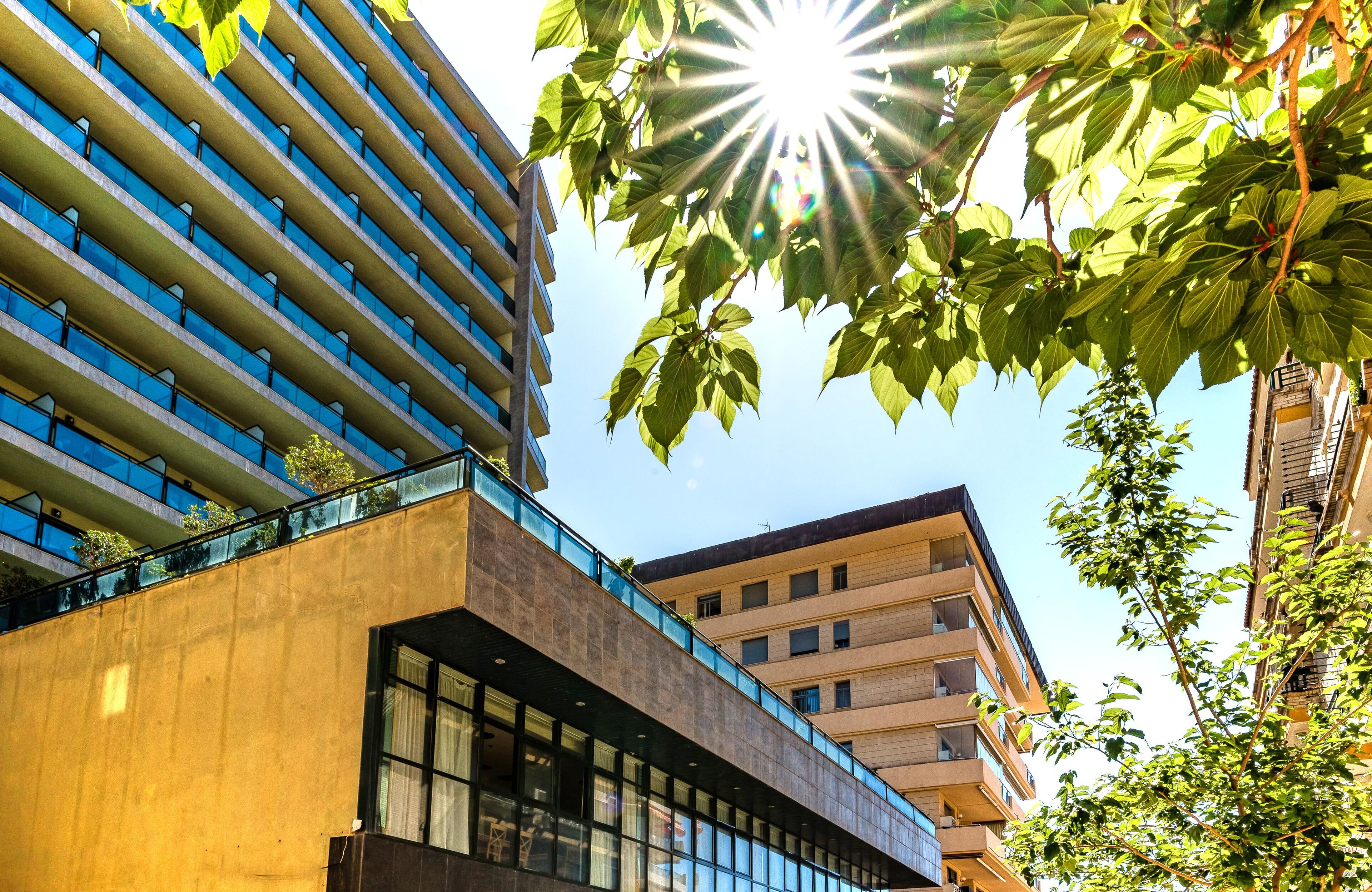 A modern building with a glass facade, large windows, and a mix of balconies and terraces.