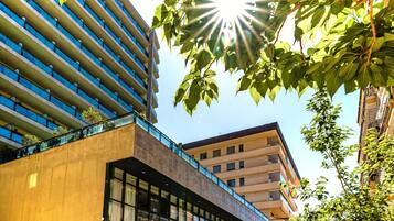 A modern building with a glass facade, large windows, and a mix of balconies and terraces.