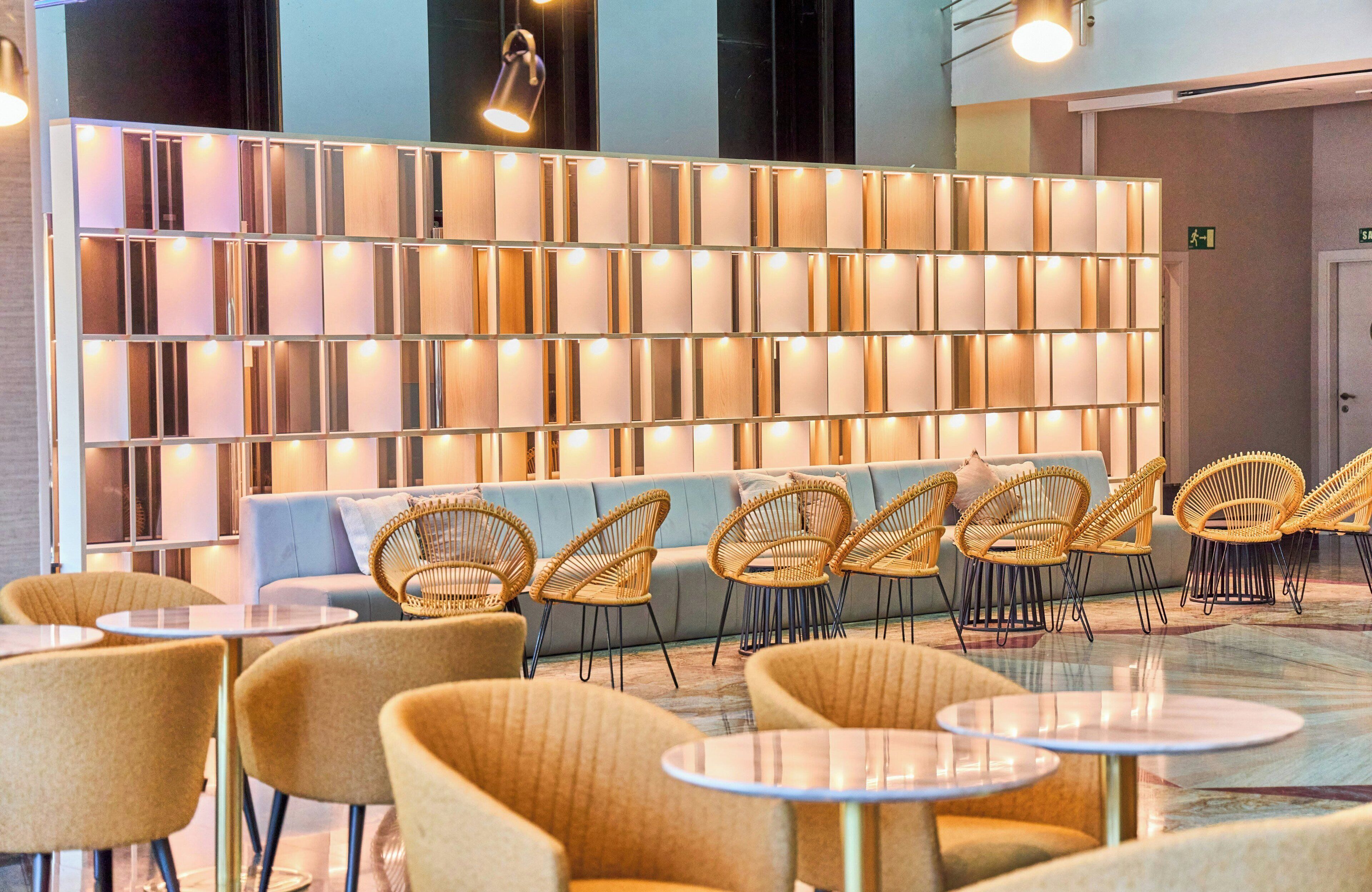 Un espace détente moderne avec un canapé, des fauteuils en osier et des tables rondes.