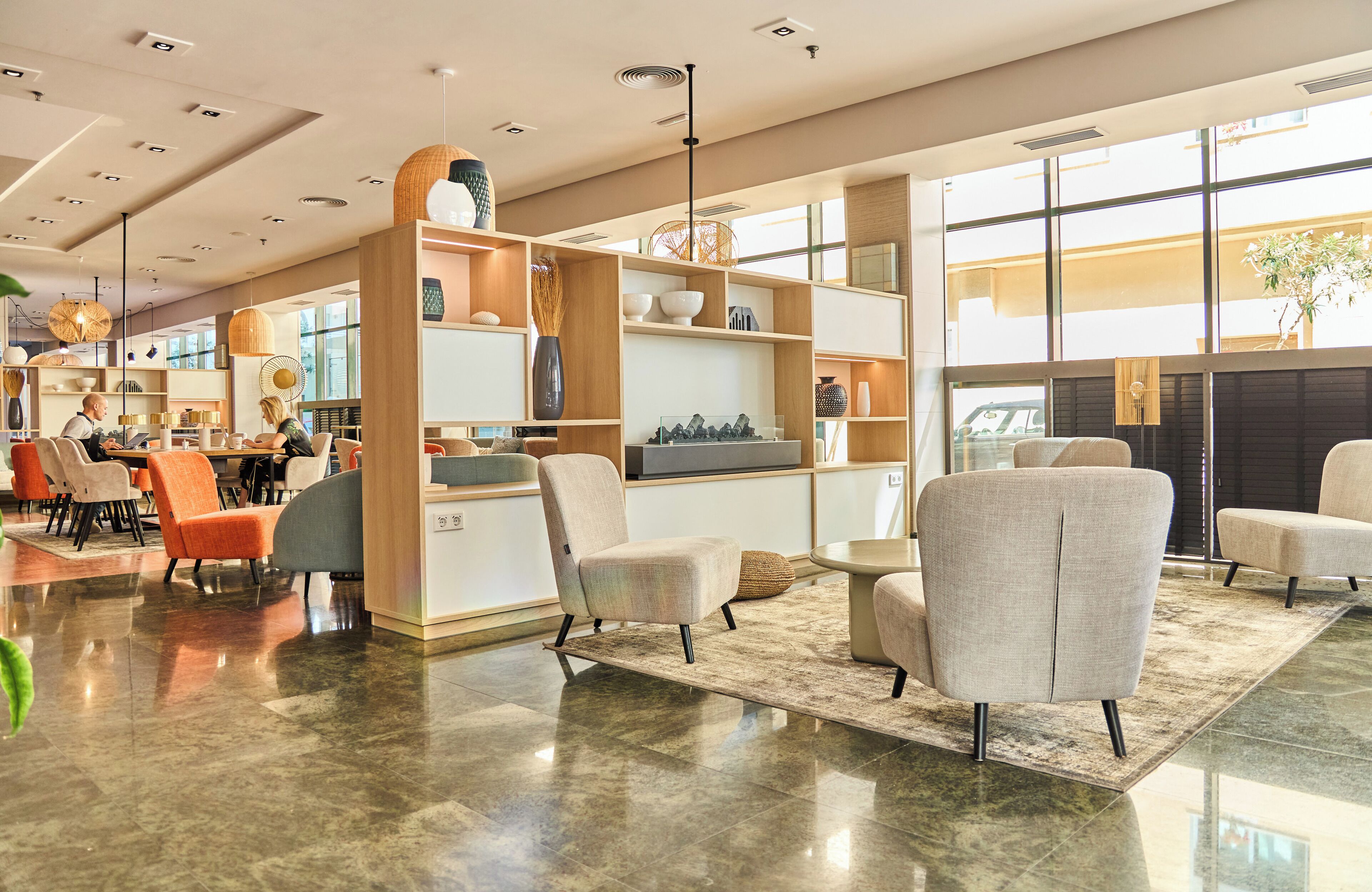 A spacious lobby with modern furniture, a central seating area, and a large window providing natural light.