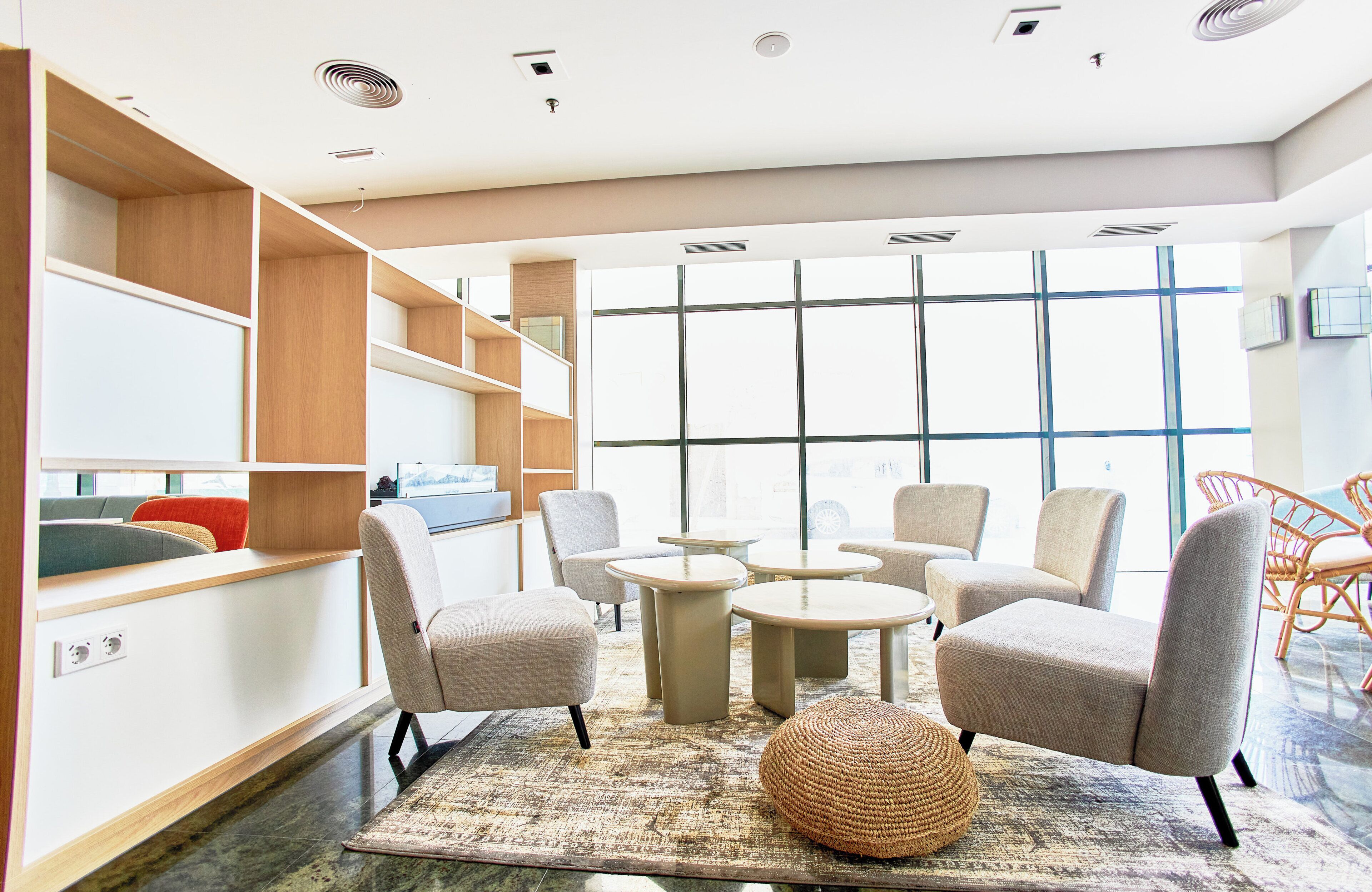 A modern lounge area with seating, tables, and built-in shelving.