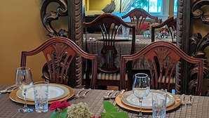 Een eettafel gedekt met borden, glazen en bestek, omringd door sierlijke houten stoelen.