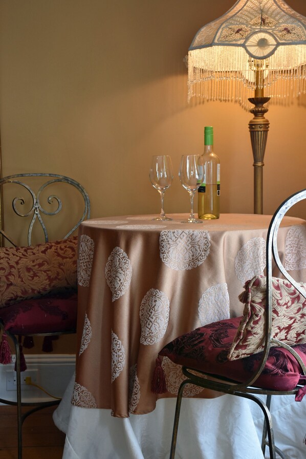 Une table dressée avec une nappe, deux verres à vin et une bouteille de vin.