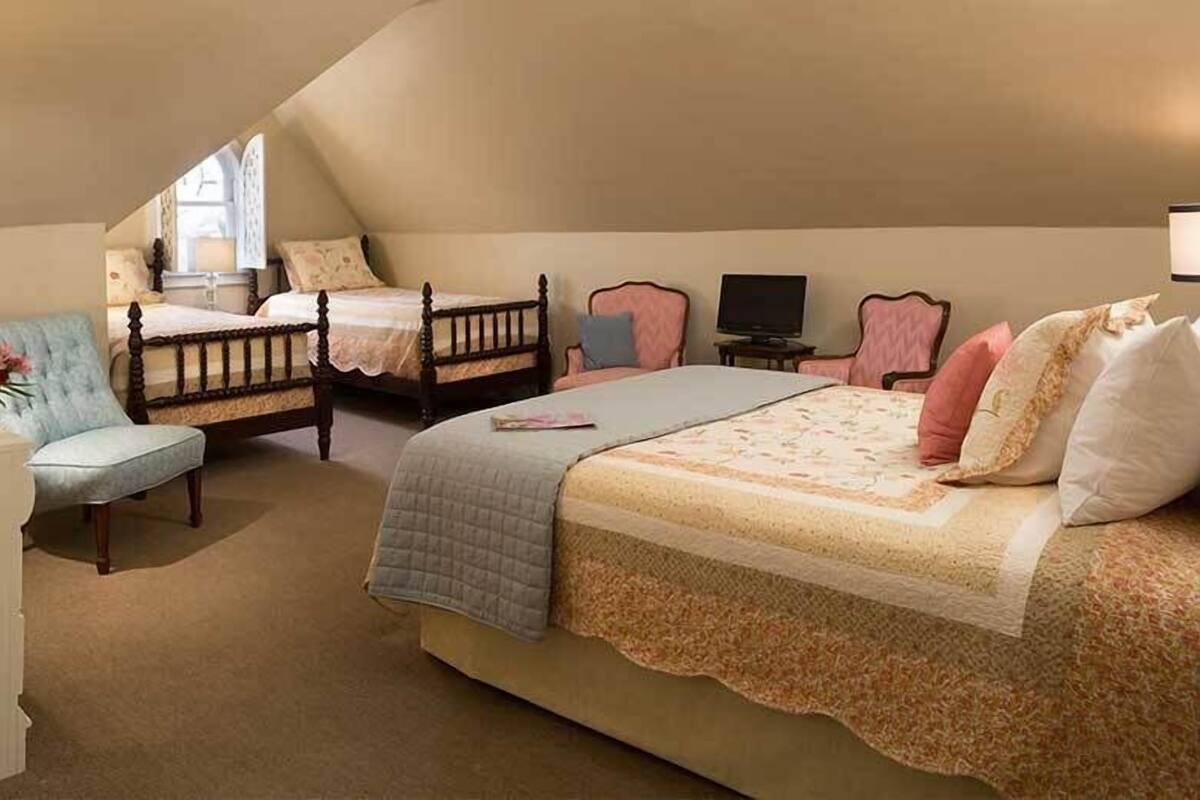 Quarto com duas camas, uma cadeira, uma televisão e uma janela.